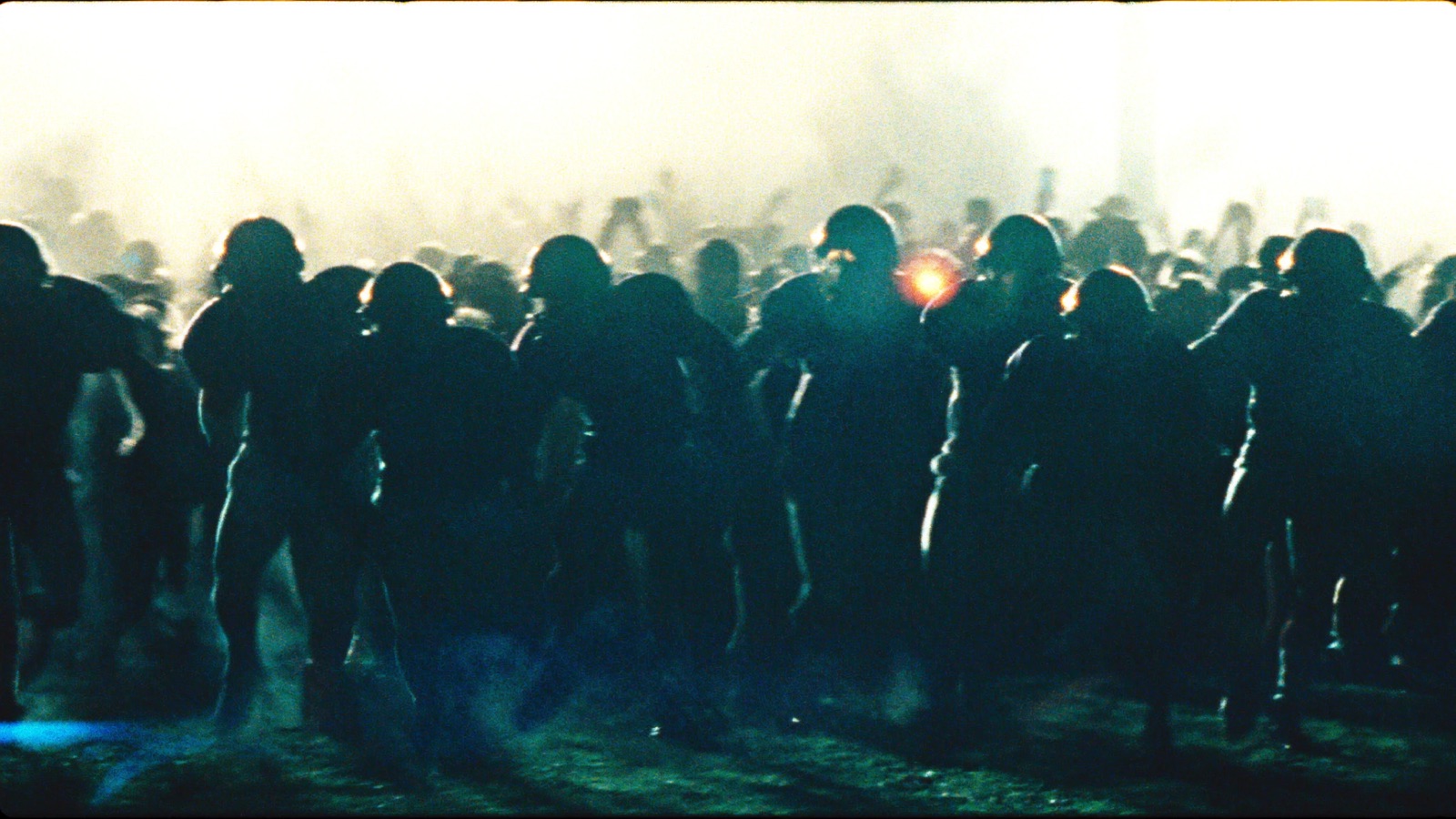 A packed line of football players silhouetted shoulder to shoulder under stadium floodlights.